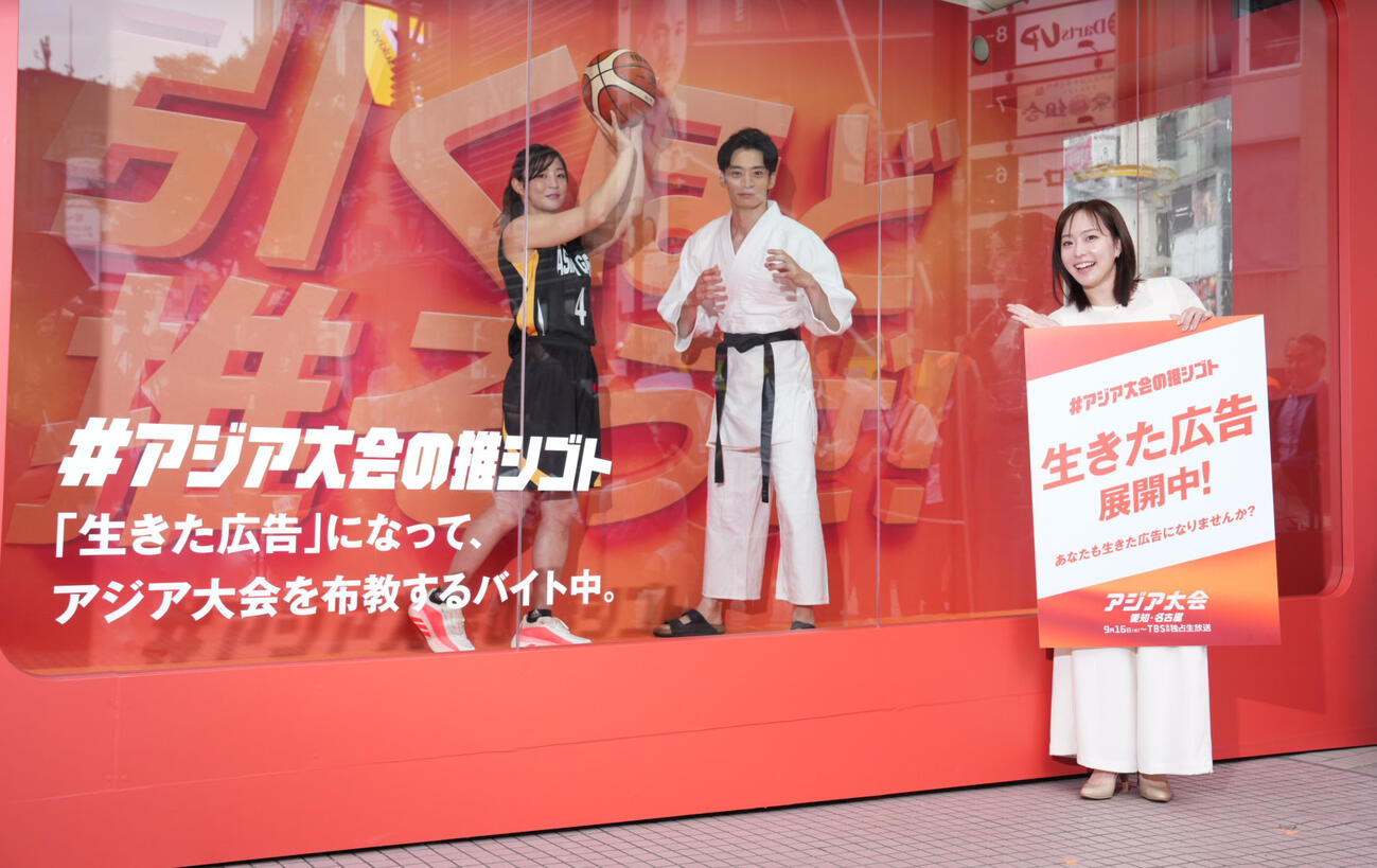 「♯アジア大会の推シゴト」メディア向け発表会・先行体験会でガラス張りのボックスに入り生きた広告を披露するアスリートアンバサダーの、左から角田夏実さん、入江陵介さん。右はスペシャルアスリートアンバサダーの石川佳純さん（撮影・小沢裕）
