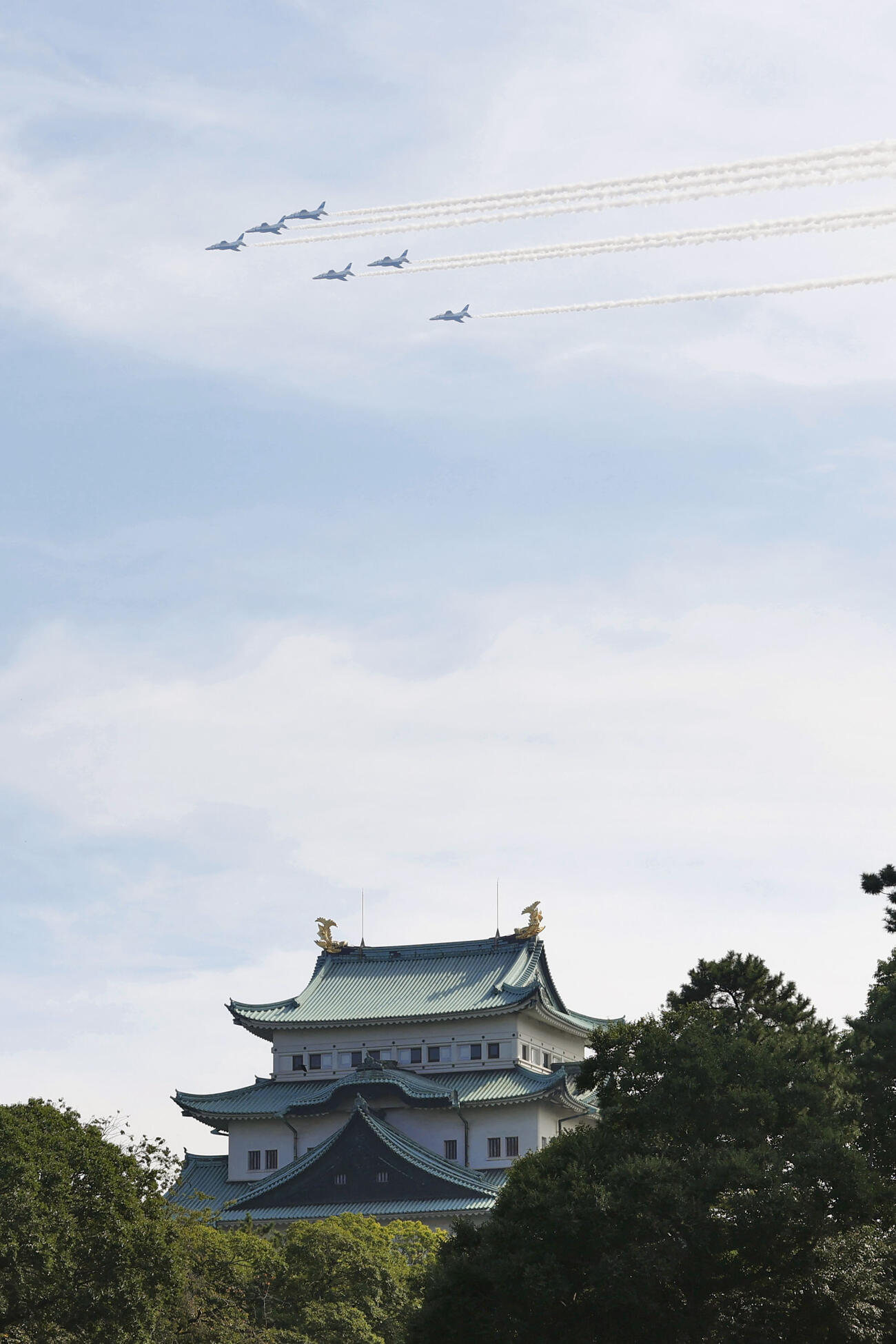 アジア大会を記念して名古屋市上空を飛行する「ブルーインパルス」。下は名古屋城天守閣（共同）