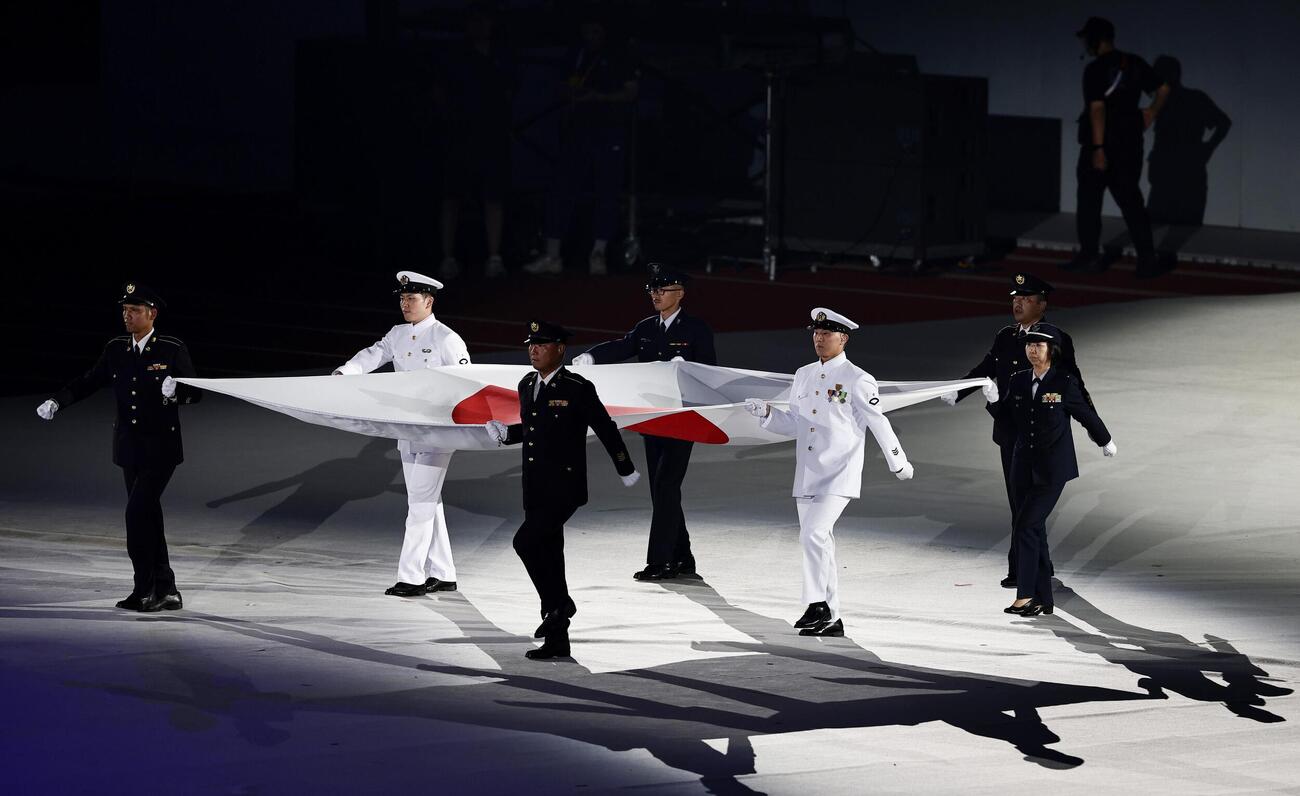 開会式で自衛隊隊員らによって運ばれる日の丸＝19日、パロマ瑞穂スタジアム（共同）