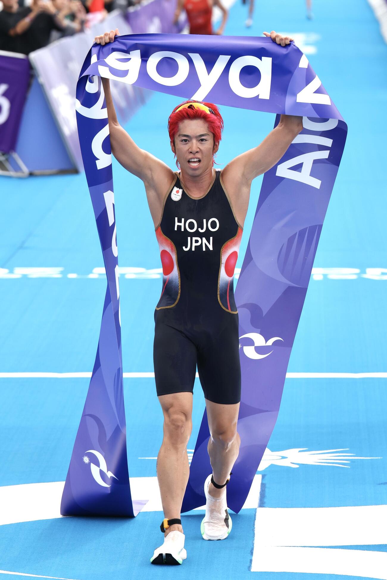 アジア大会トライアスロン男子で優勝し、ゴールテープを持ち上げる北條巧。日本勢金メダル1号となった（撮影・宮地輝）