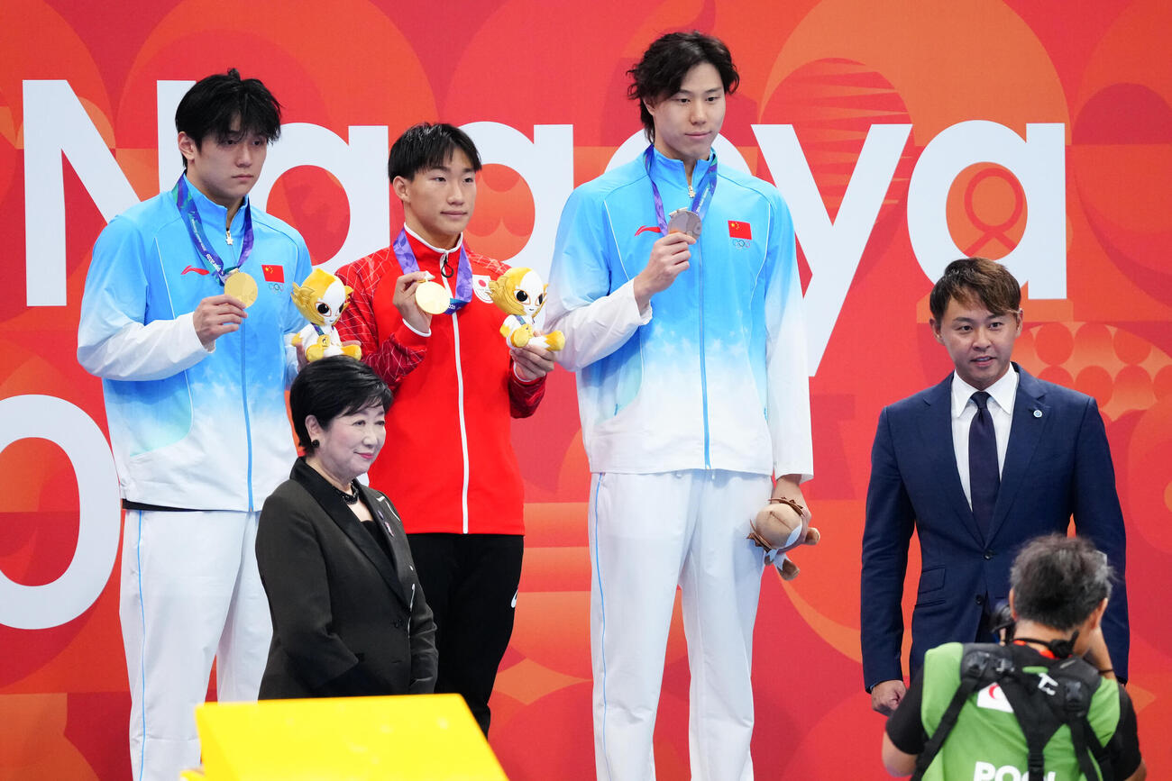 男子100メートル平泳ぎ決勝　金メダルを獲得し、表彰台で記念撮影に納まる大橋信（中央）。前列左は北島康介氏、同右は小池百合子都知事（撮影・鈴木みどり）