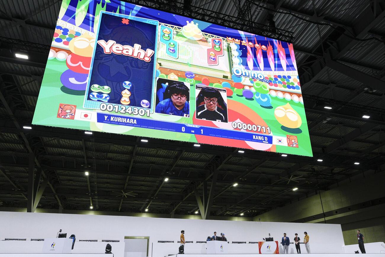 「ぷよぷよ」決勝で韓国選手（右）と対戦する栗原悠輝を映す大型画面＝愛知県国際展示場