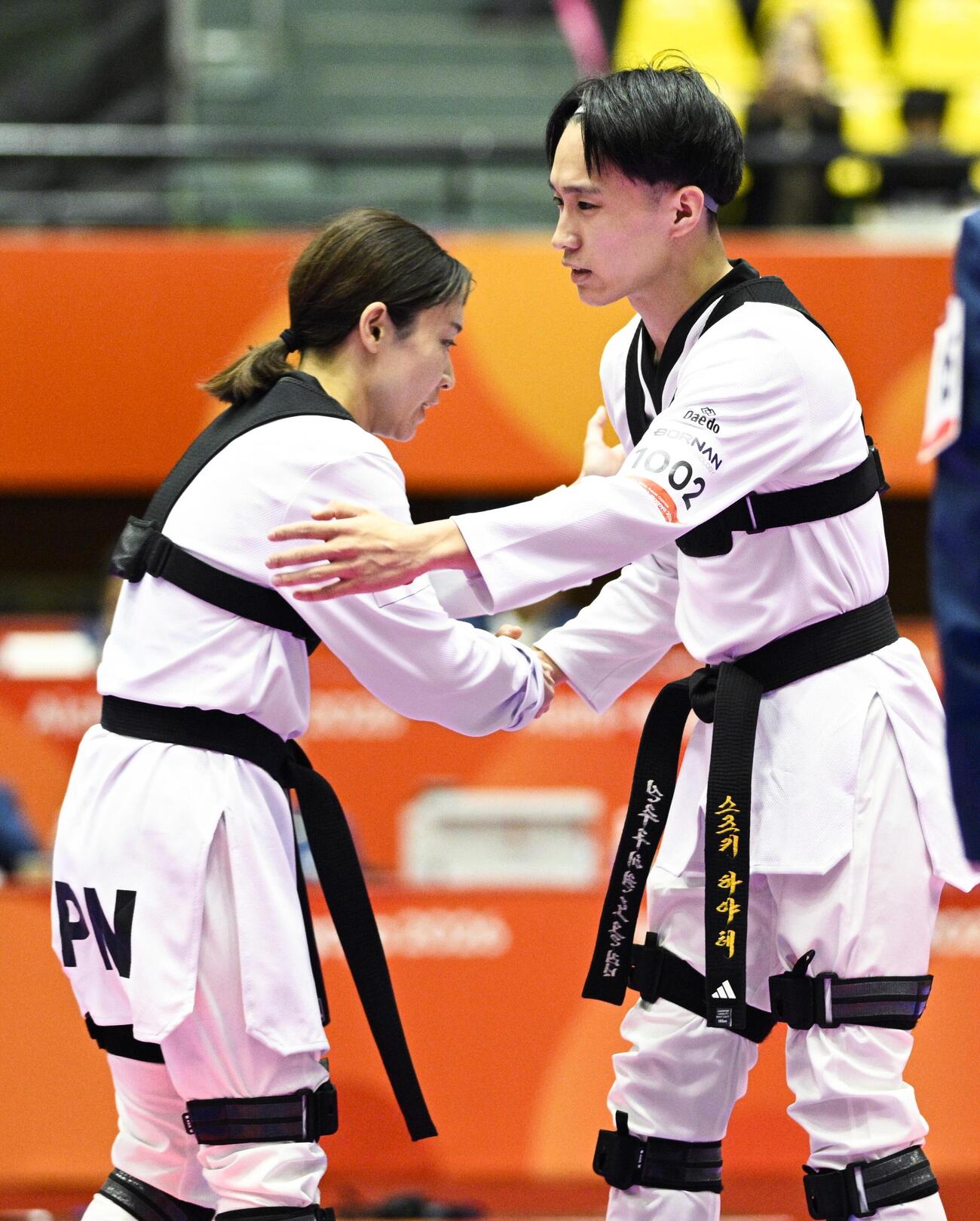 バーチャルテコンドー1回戦で中島美鳳（左）に勝利し、握手する鈴木颯＝2日、愛知県の豊橋市総合体育館（共同）