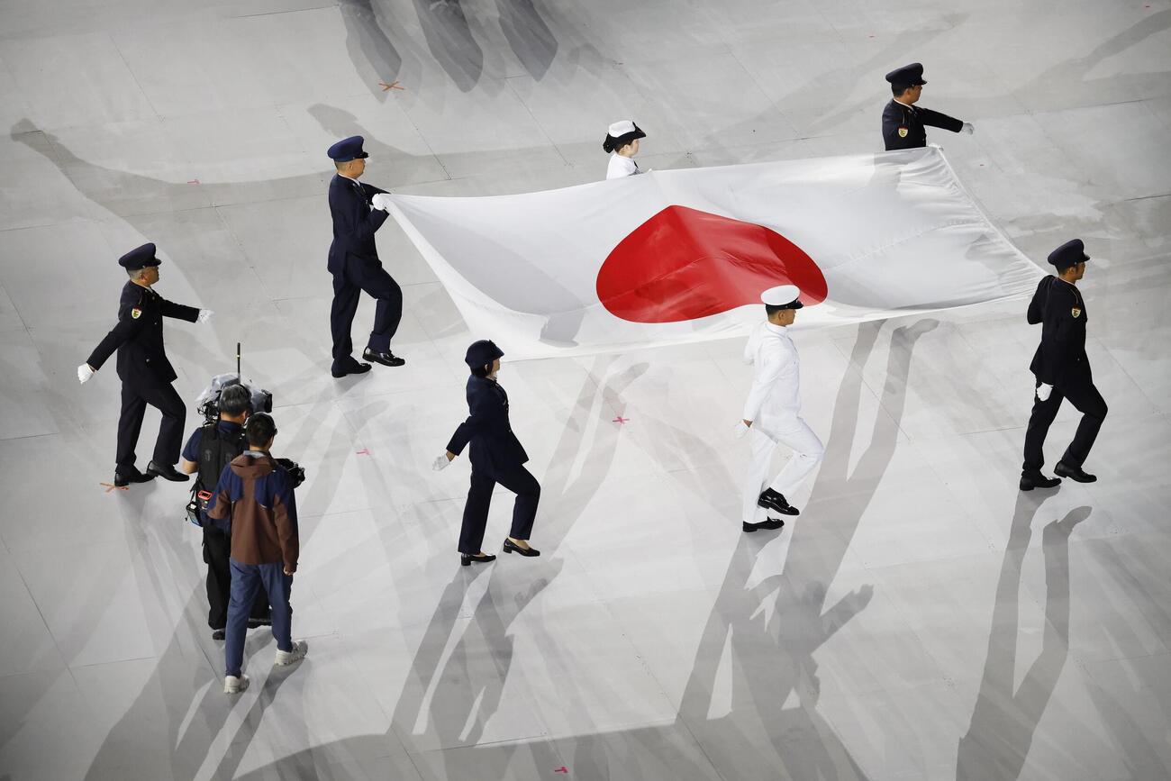 閉会式で運ばれる日の丸（共同）