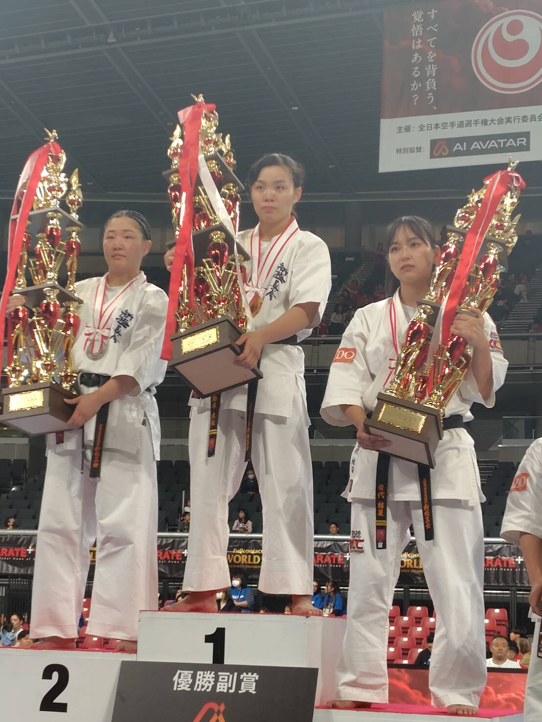 全日本空手道選手権・組手女子の表彰式でトロフィーを掲げる優勝した鈴木未紘（中）、準優勝の藤原桃萌、第3位の目代結菜