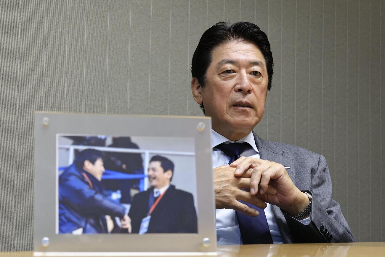 インタビューに応じる日本ラグビー協会の土田雅人会長。手前は平尾誠二さんとの写真