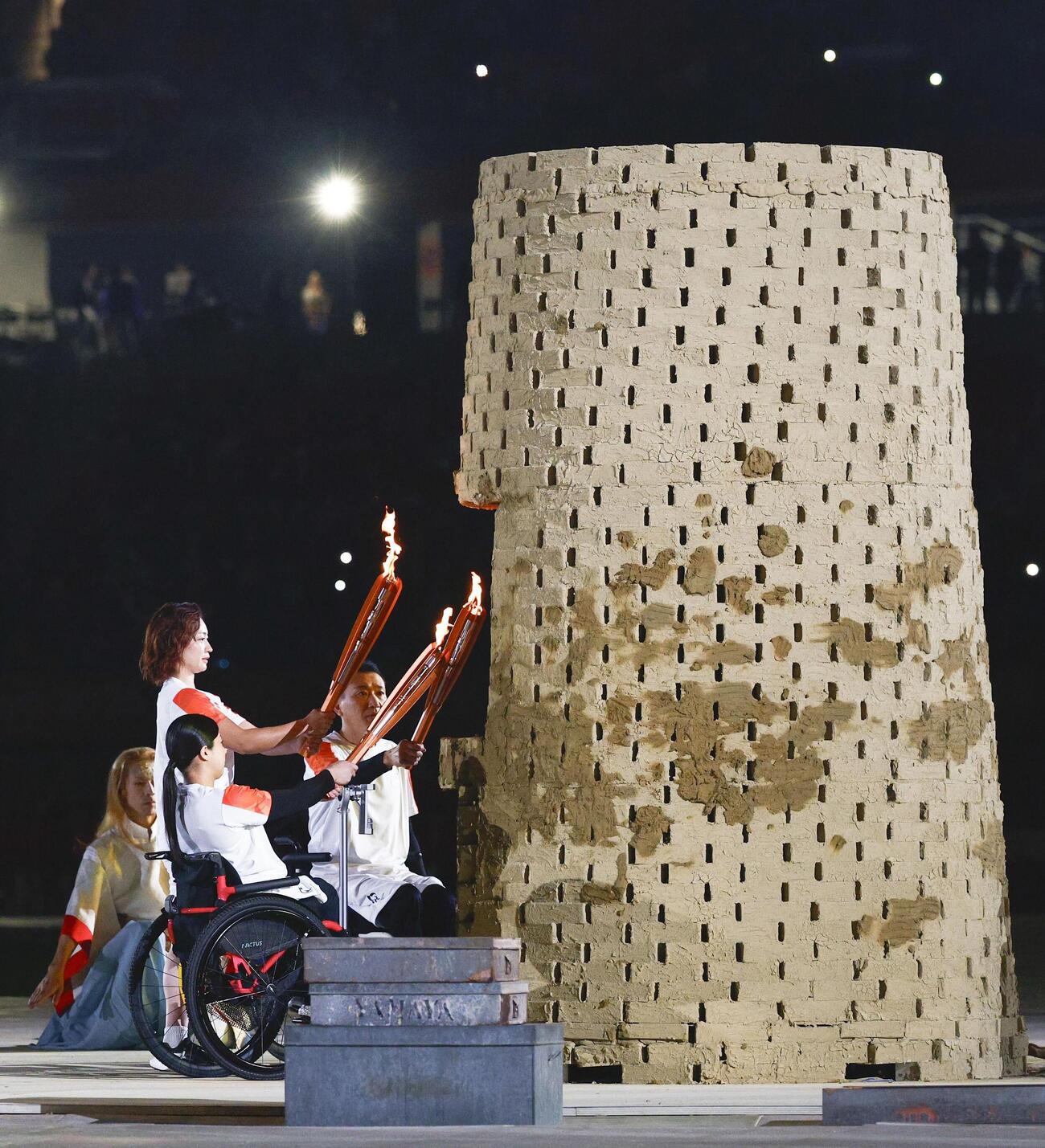 愛知・名古屋アジアパラ大会の開会式で、聖火台に点火するリレー最終走者の（手前から）村岡桃佳さん、中西麻耶さん、三宅克己さん＝18日、名古屋市のパロマ瑞穂スタジアム（共同）