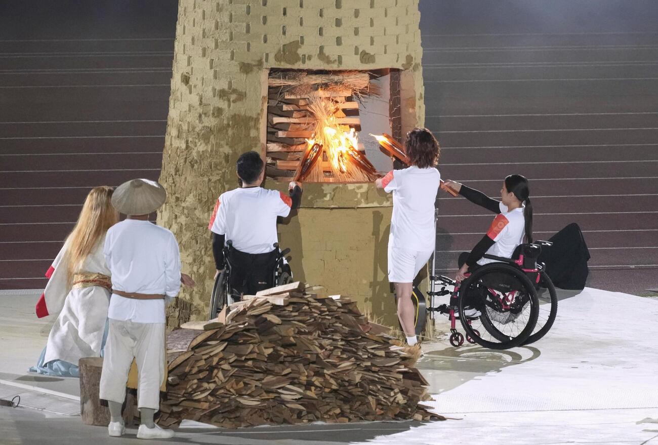 開会式で聖火台に点火するリレー最終走者の（右から）村岡桃佳さん、中西麻耶さん、三宅克己さん＝18日、パロマ瑞穂スタジアム（共同）
