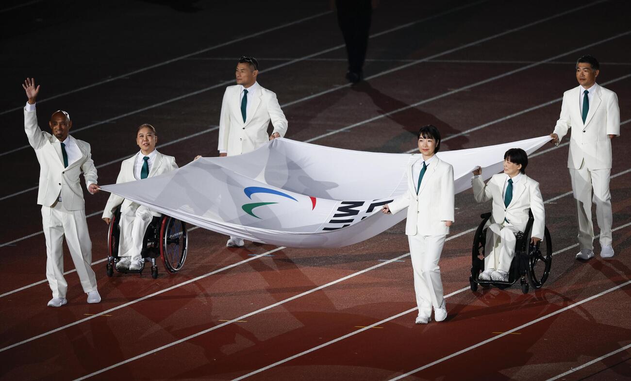 開会式で運ばれる大会旗＝18日、パロマ瑞穂スタジアム（共同）