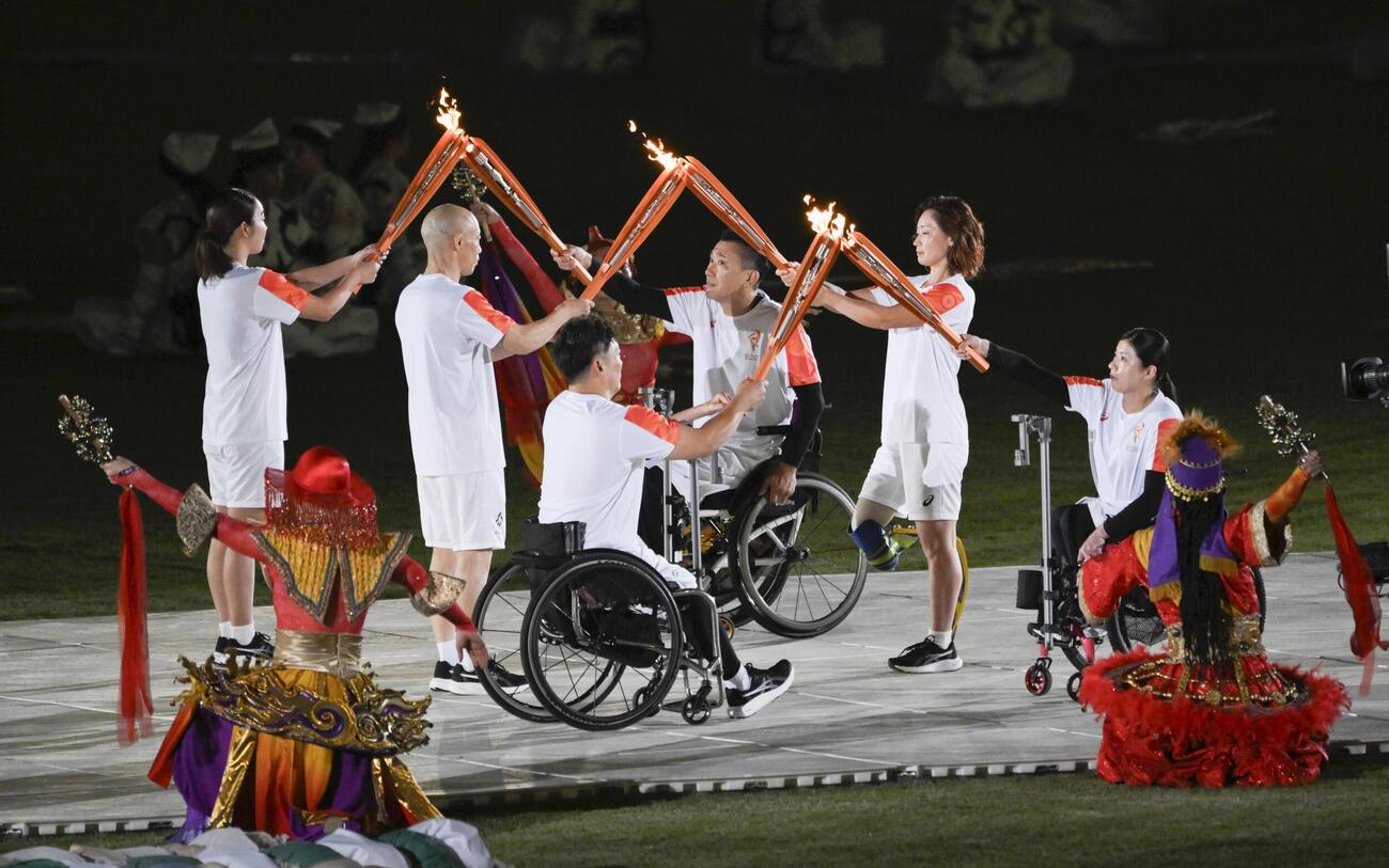 開会式で聖火を受け継ぐリレー最終走者の（右から）村岡桃佳さん、中西麻耶さん、三宅克己さん＝18日、パロマ瑞穂スタジアム（共同）