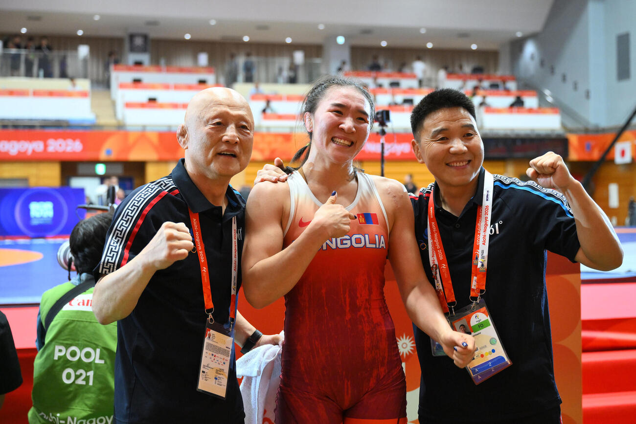 10月1日、愛知・名古屋アジア大会レスリング女子62キロ級でモンゴルのトグトフ・アルトジン（中央）が銅メダルを獲得し記念撮影する栄和人総監督（左）（撮影・滝沢徹郎）