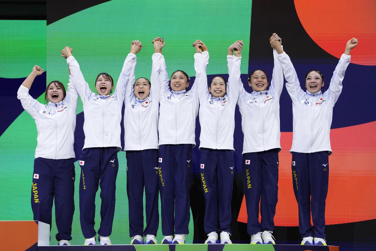 体操世界選手権の女子団体総合で銅メダルを獲得し、表彰台で喜ぶ日本の選手ら。ロサンゼルス五輪の切符を手にした＝21日、オランダ・ロッテルダム（共同）