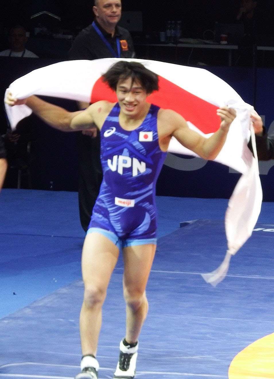 男子グレコローマン60キロ級で優勝し、日の丸を掲げて走る五味虹登＝アスタナ（共同）