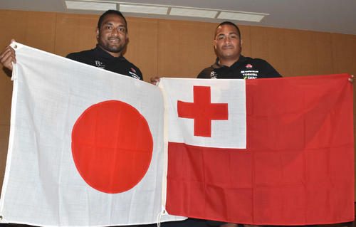 日本国旗を持つラグビー日本代表候補プロップの中島イシレリ（左）と母国トンガの国旗を持つ同プロップのバル・アサエリ愛