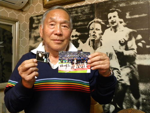 07年W杯フランス大会開会式典の写真とピンバッジを手にする坂田好弘氏（撮影・松本航）