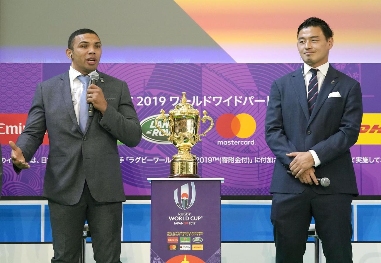 ラグビーW杯の優勝杯「ウェブ・エリス・カップ」を前に話す元南アフリカ代表のブライアン・ハバナ氏（左）と五郎丸歩（共同）