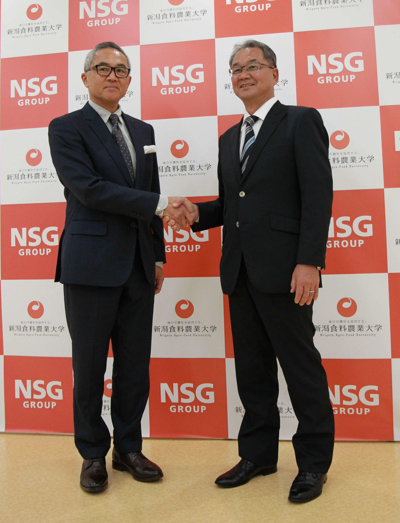 新潟食農大・中井副学長（左）と笑顔で握手を交わす谷崎監督