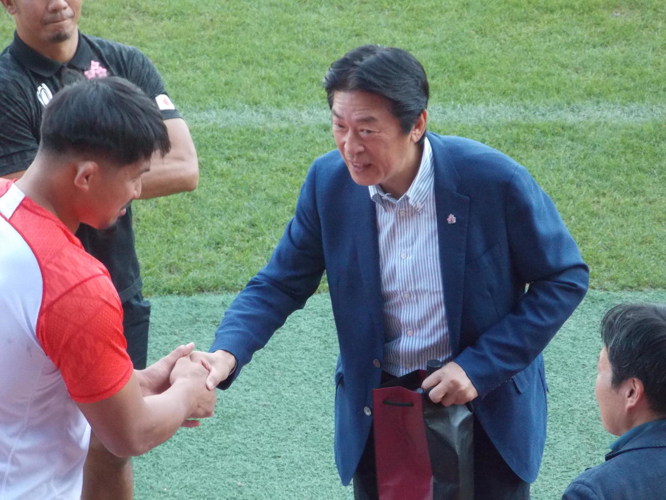 日本のサモア戦前日練習に訪れた日本協会の土田雅人会長（右）は姫野和樹主将と握手する