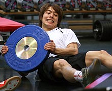 バーベルのプレートを抱えながら腹筋を鍛える宮崎（撮影・鈴木豊）