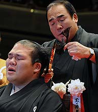 栃東（左）の断髪式で大銀ちょうにはさみを入れる師匠の玉ノ井親方